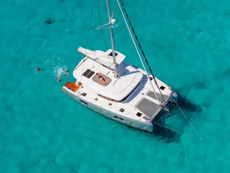 Aerial view of the Lagoon 42 catamaran at anchor over turquoise shallows