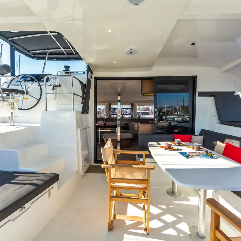 Shaded cockpit of the Lagoon 42 with a large dining table and cushioned seating