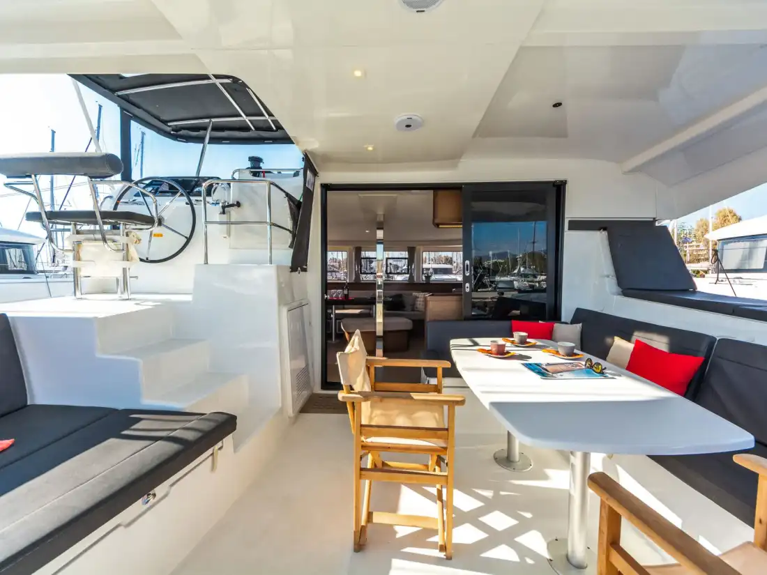 Shaded cockpit of the Lagoon 42 with a large dining table and cushioned seating